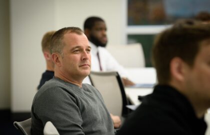A group of people is sitting in a classroom setting, listening attentively, as they delve into the intricacies of organizational leadership.