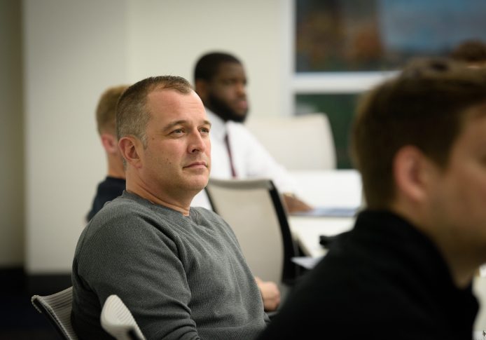 A group of people is sitting in a classroom setting, listening attentively, as they delve into the intricacies of organizational leadership.