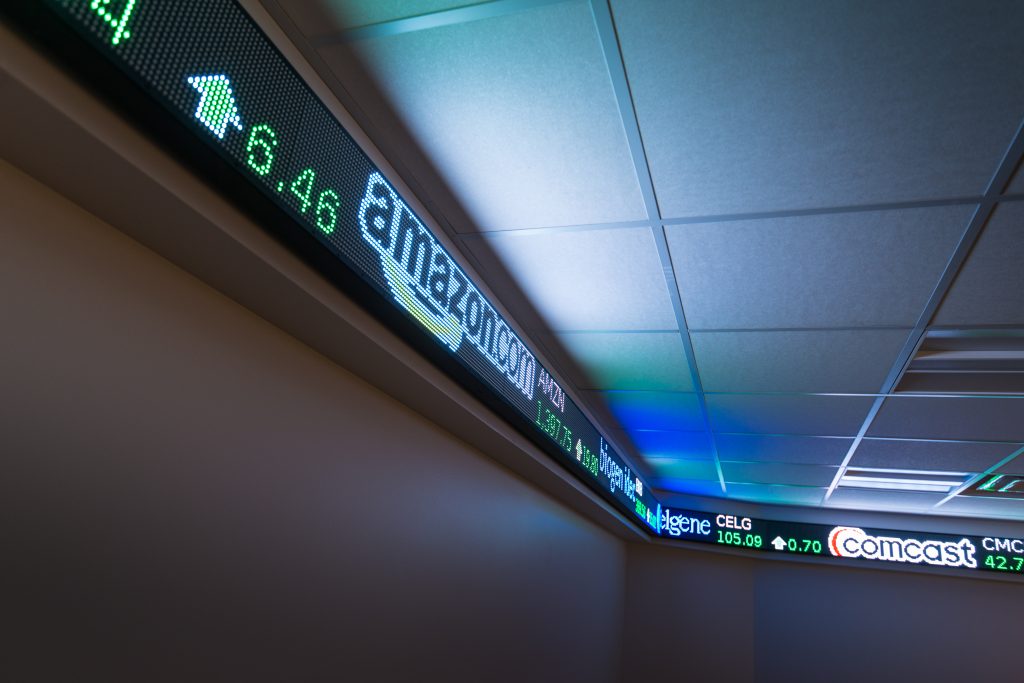 The LED stock ticker display, featuring company names and stock prices like Amazon and Comcast, illuminates the ceiling background at the Finance Association of Northwood University.