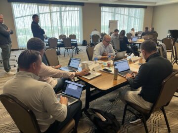 Automotive professionals demonstrate leadership as they work on laptops around a conference table in the meeting room.