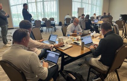 Automotive professionals demonstrate leadership as they work on laptops around a conference table in the meeting room.