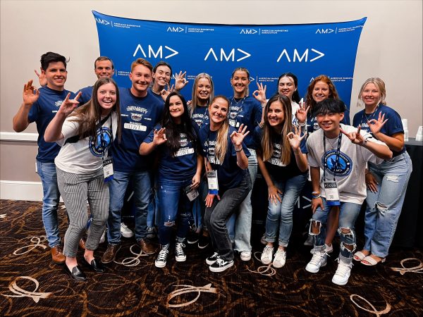 AMA students standing together in Northwood apparel, holding their thumb and pointer fingers together.