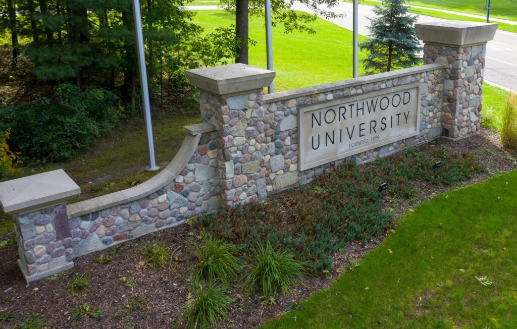 A stone sign reading "Northwood University Founded 1959" sits gracefully amid lush greenery and trees, a testament to the institution's legacy. Recently, the university received recognition from Intelligent.com for its excellence, adding to NU awards over the years.