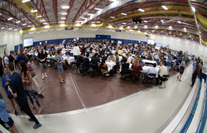 A fisheye camera angle of the College Fair, a room full of people