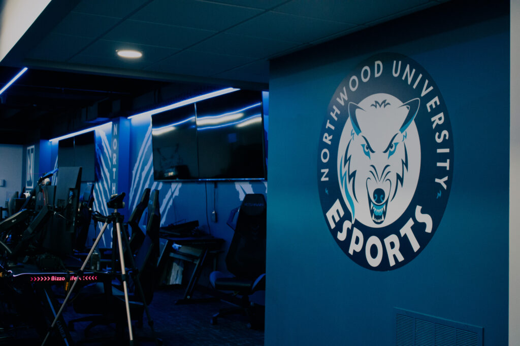 The esports room at Northwood University features Auto Draft gaming chairs, high-performance monitors, and a striking wall logo showcasing a wolf.