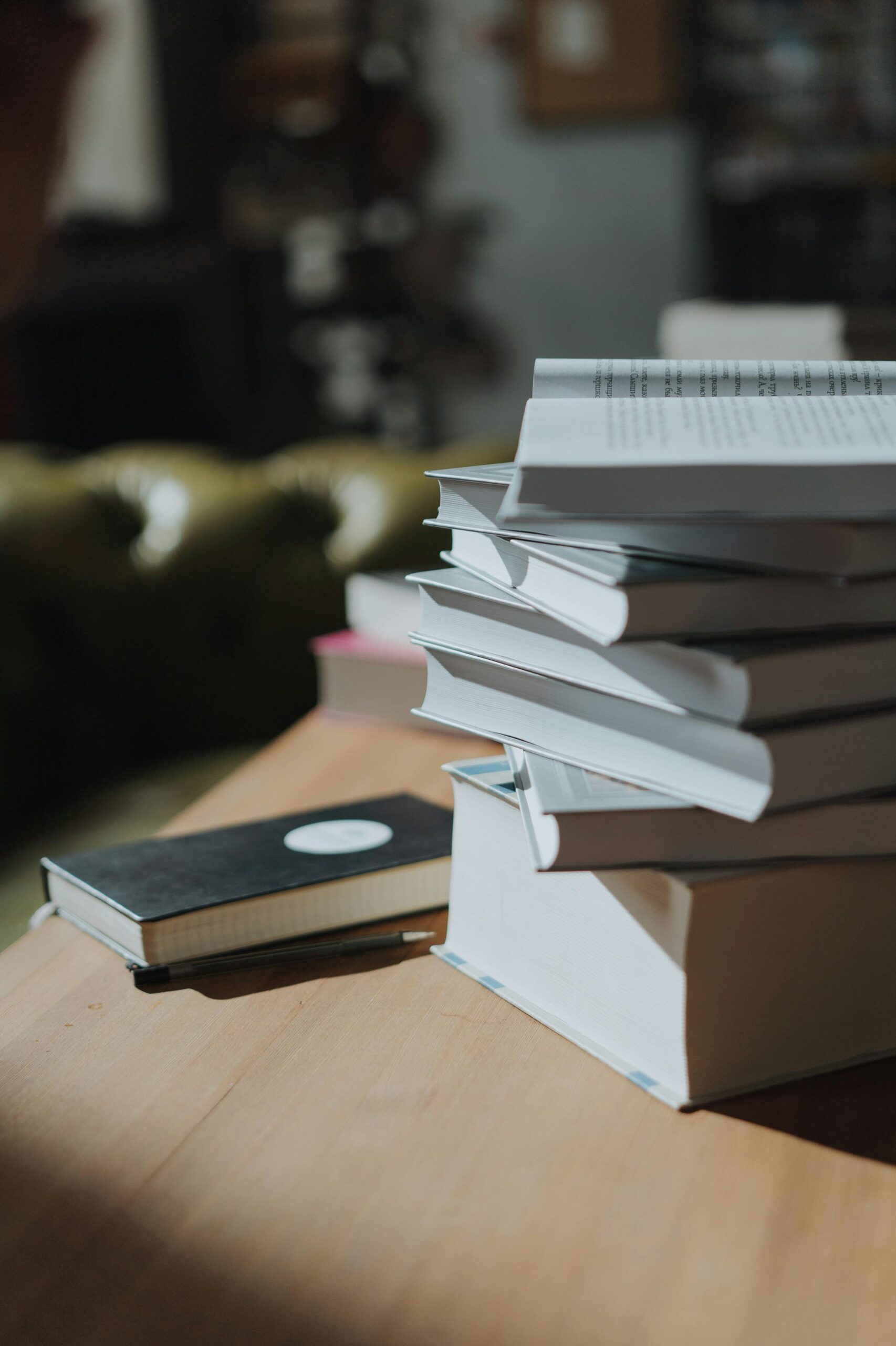 A stack of open and closed books rests on a wooden table, accompanied by a notebook, lending an air of scholarly charm.