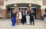 A group of people in formal attire stand on the steps of Joseph E. Keller Hall, posing for a photo.