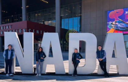 Four people stand in front of large "NADA" letters outside a convention center with modern glass architecture, capturing a moment for the Driven Newsletter in February 2025.