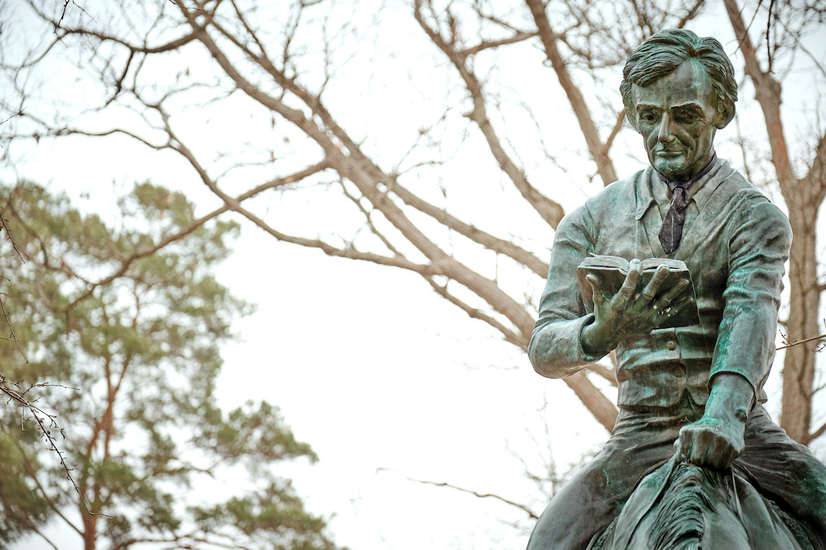 Bronze statue of a man sitting on a horse, reading a book, with trees in the background, symbolizing the pursuit of knowledge inspired by the Northwood Idea at Northwood University.