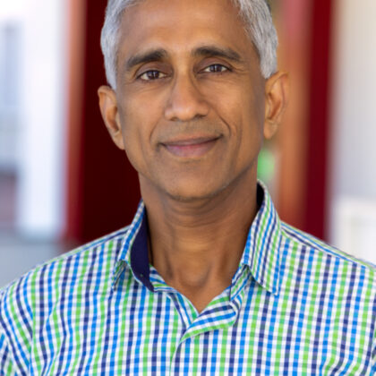 Dr. Srikanth Srinivasa, a middle-aged man with short gray hair, stands indoors in a green and blue checkered shirt, looking at the camera with a neutral expression.