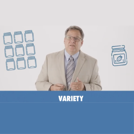A man in a light suit stands in front of illustrated jars and the word "VARIETY" on a blue background bar, symbolizing the freedom of choice found in a thriving free enterprise system.