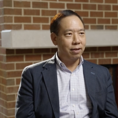 A man in a suit jacket and checked shirt sits indoors in front of a brick wall, facing slightly to the right—captured during a discussion at the Center for Automotive and Mobility Studies.