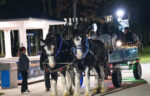 Two decorated horses pull a lit-up wagon with people on board at night, near a Northwestern University sign and a small pavilion—capturing the spirit of Winter Wonderland enhancements on Dec. 9.