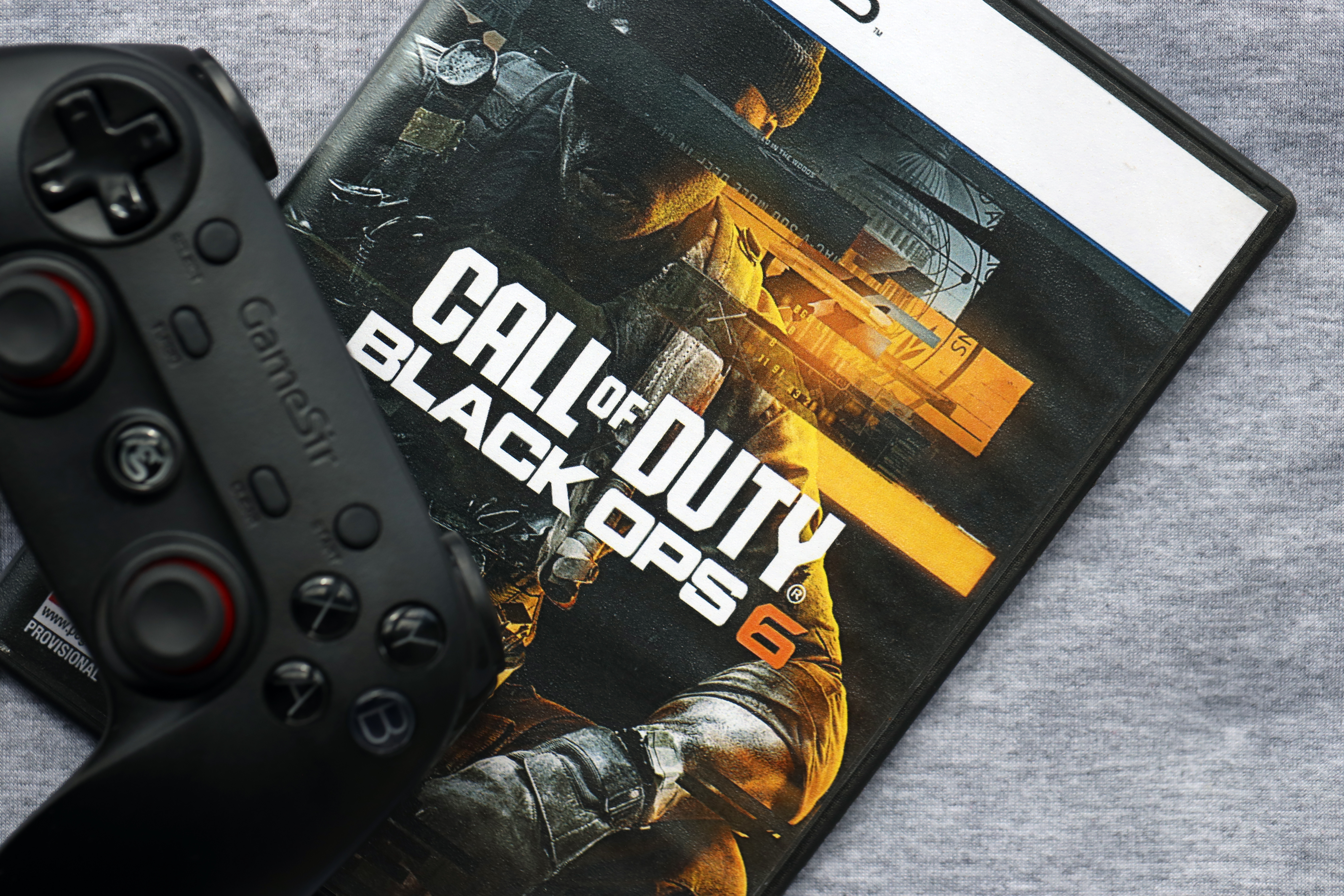 A PlayStation controller rests on top of a "Call of Duty: Black Ops 6" game case, both placed on a gray surface—echoing the dedication seen in Northwood Esports as they chase national titles.