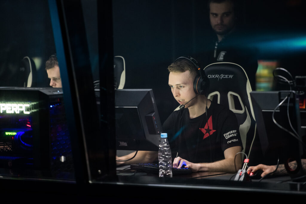A person wearing headphones and a black t-shirt is focused on a computer screen while participating in a Northwood Esports competition, sitting in a gaming chair.