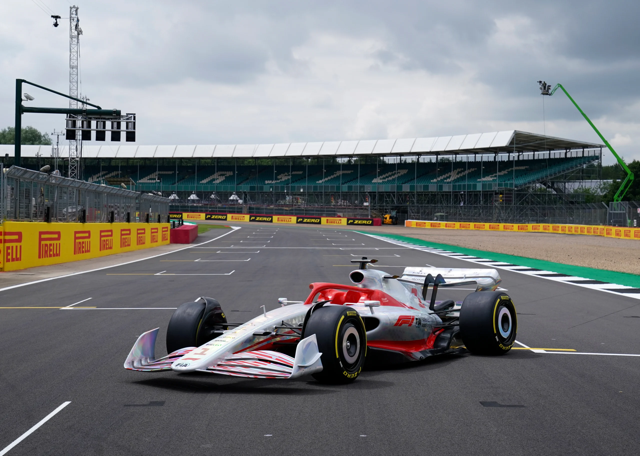 A modern Formula 1 car is stationary on a racetrack in front of empty grandstands under a cloudy sky, capturing the perfect moment for a Friends Trip or a memorable outing with classmates from Northwood University.