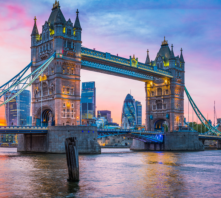 Tower Bridge in London spans the River Thames at sunset, with modern city buildings in the background—a perfect spot for memorable photos on your family trip or friends trip.