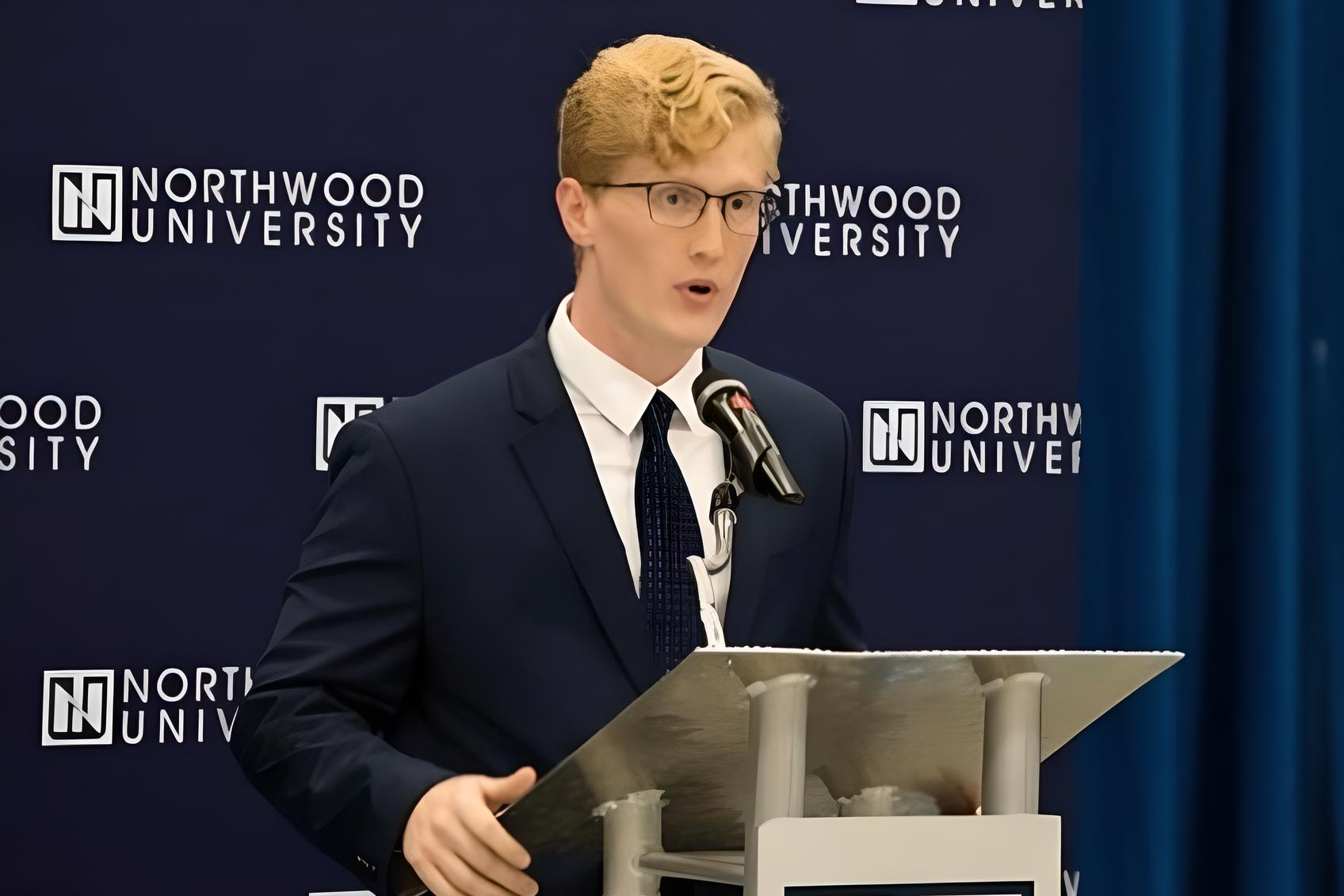 A person in a suit speaks at a podium with a microphone, emphasizing the importance of insurance risk management. The background displays "Northwood University" repeatedly.