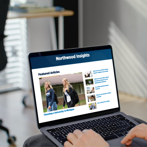 A person uses a laptop displaying a website called "Northwood Insights," featuring articles and a main image of two people walking outdoors.