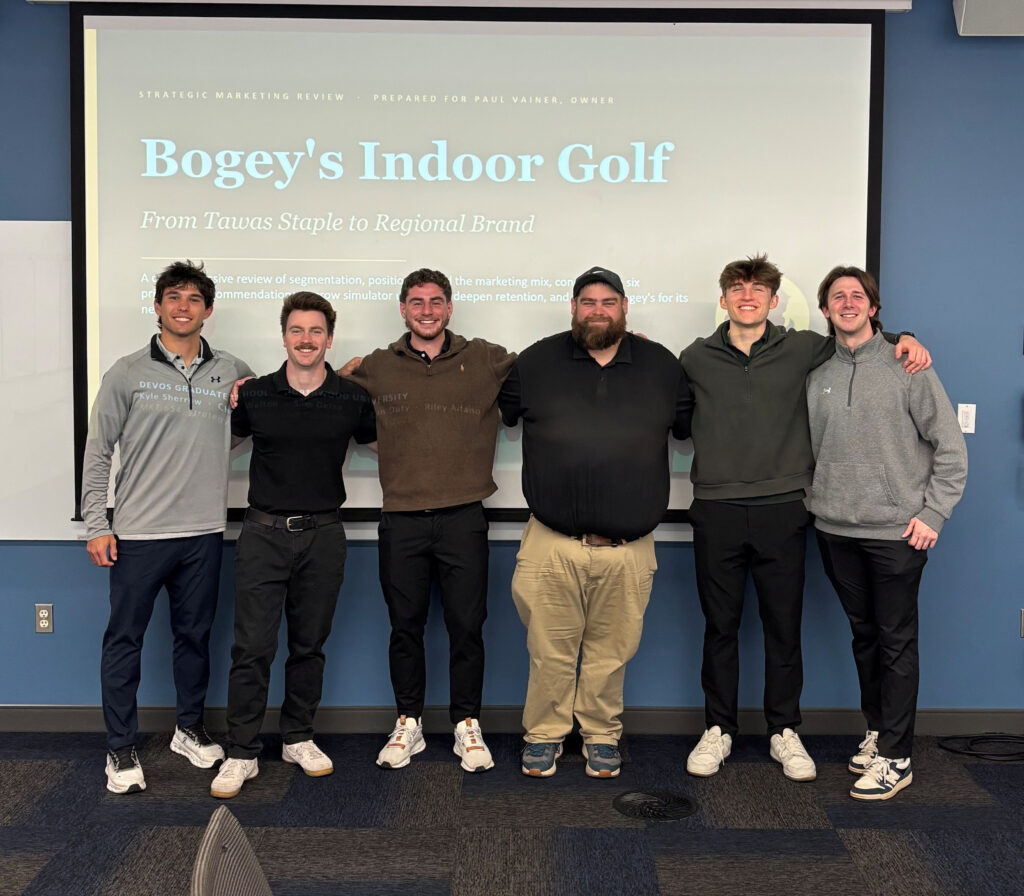 Six men stand side by side, smiling in front of a presentation slide titled "Bogey's Indoor Golf" in a conference room.