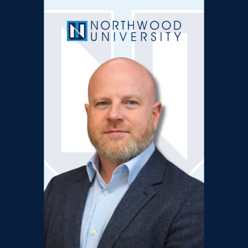 A man in a blue blazer and light blue shirt stands in front of a Northwood University logo backdrop.