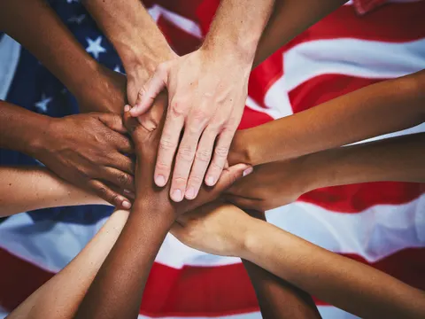 A group of diverse hands stacked together in unity, with an American flag visible in the background, captures the spirit of Northwood coming together as one community.