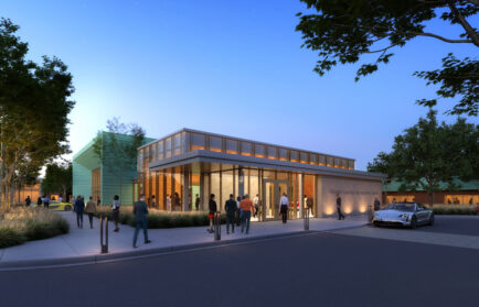 People stand and walk near a modern, well-lit building with large windows at dusk; a car is parked nearby and trees line the surrounding area, highlighting this impressive new rendering of the Northwood University academic facility.