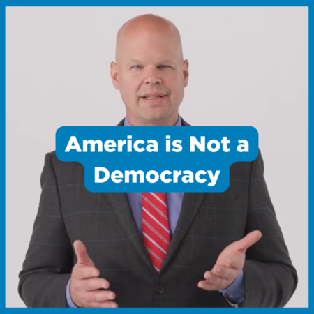 Bald man in a suit and red striped tie gestures with hands. Text overlay reads, โAmerica is Not a Democracyโ on a plain background, offering a thought-provoking perspective for Constitution Day.