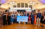 A group of people in formal attire pose indoors holding a large check from Northwood University for $50,048.19, dated September 14, 2022.