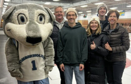 A group of five people poses with a Timberwolves mascot on an indoor curling rink during a fundraiser event.