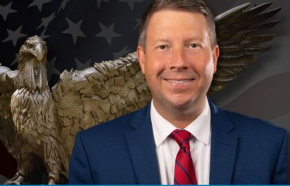 Portrait of ALEC’s Jonathon Williams for a Northwood University Freedom Seminar, with an eagle statue and American flag in the background.