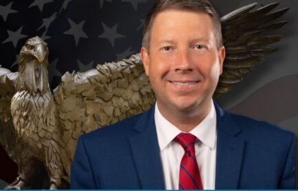 Portrait of ALEC’s Jonathon Williams for a Northwood University Freedom Seminar, with an eagle statue and American flag in the background.