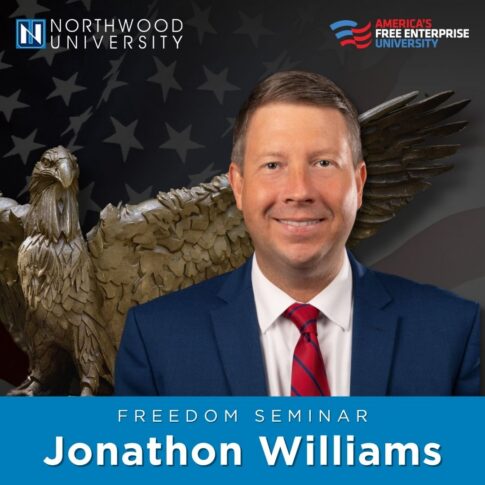 Portrait of ALEC’s Jonathon Williams for a Northwood University Freedom Seminar, with an eagle statue and American flag in the background.