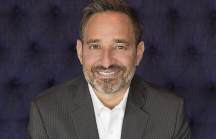 A middle-aged man with a beard, wearing a white shirt and dark blazer, smiling at the camera.