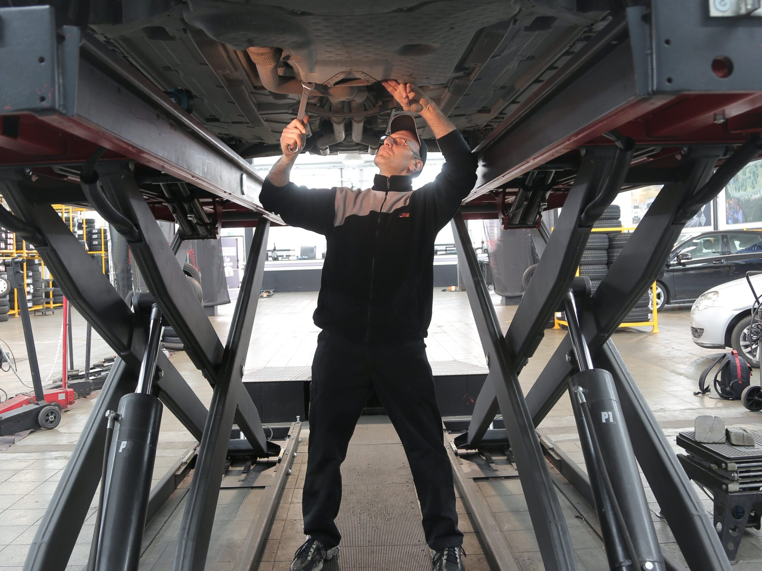Man standing under a car in an automobile shop