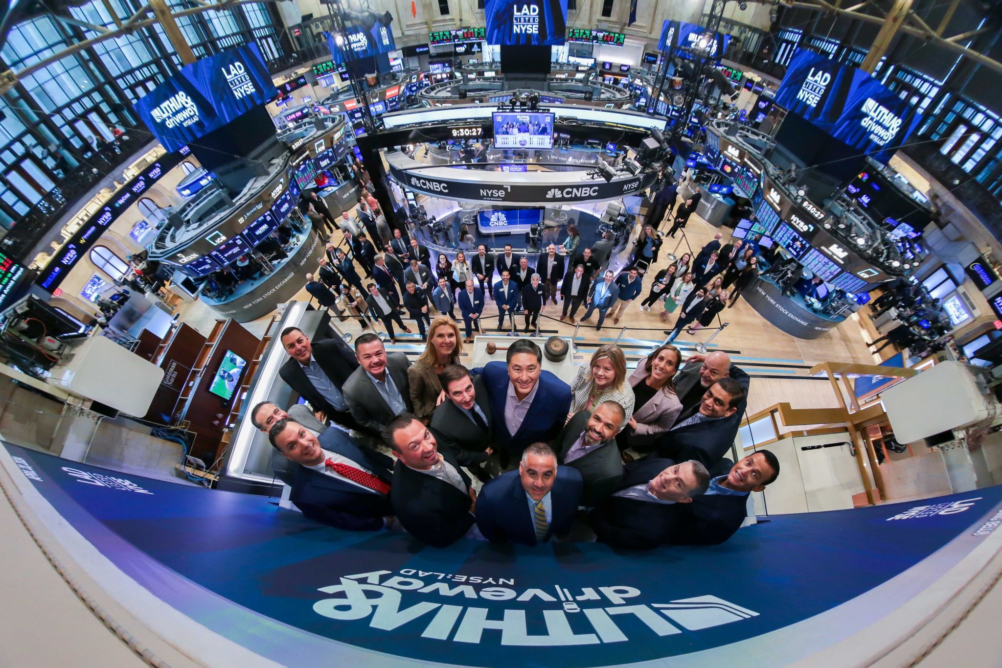 Group of people posing on a trading floor with digital displays and monitors surrounding them.