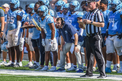 A hyped football team and staff standing on the sidelines during a game