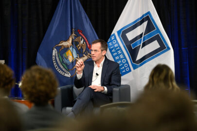 A photo of Bob Kron at leadership insights. The Michigan flag and Northwood University flag are staged behind him.