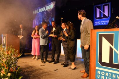 Reynolds and Reynolds receiving an award on stage with ,000,000 display on a screen with fireworks and smoke.