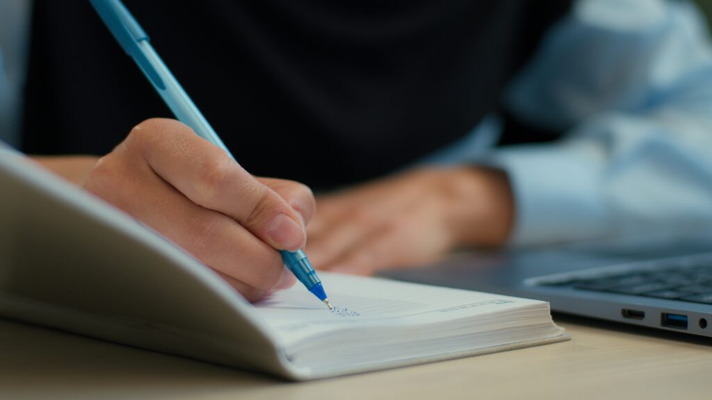 Cropped student writing down notes.
