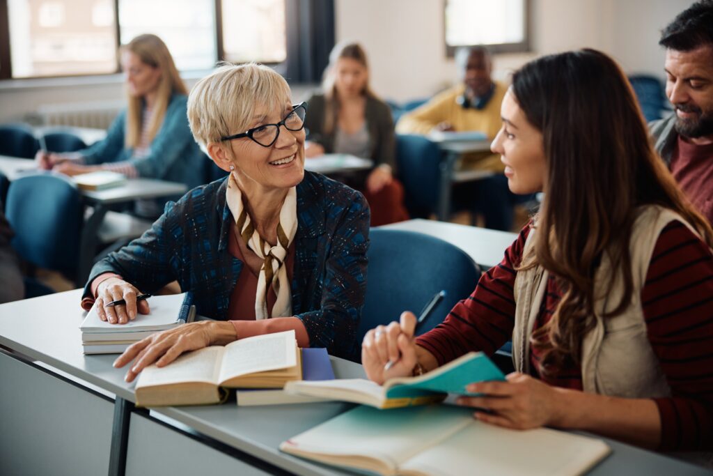 Smiling female adult learners communicating during a class in lecture hall.
