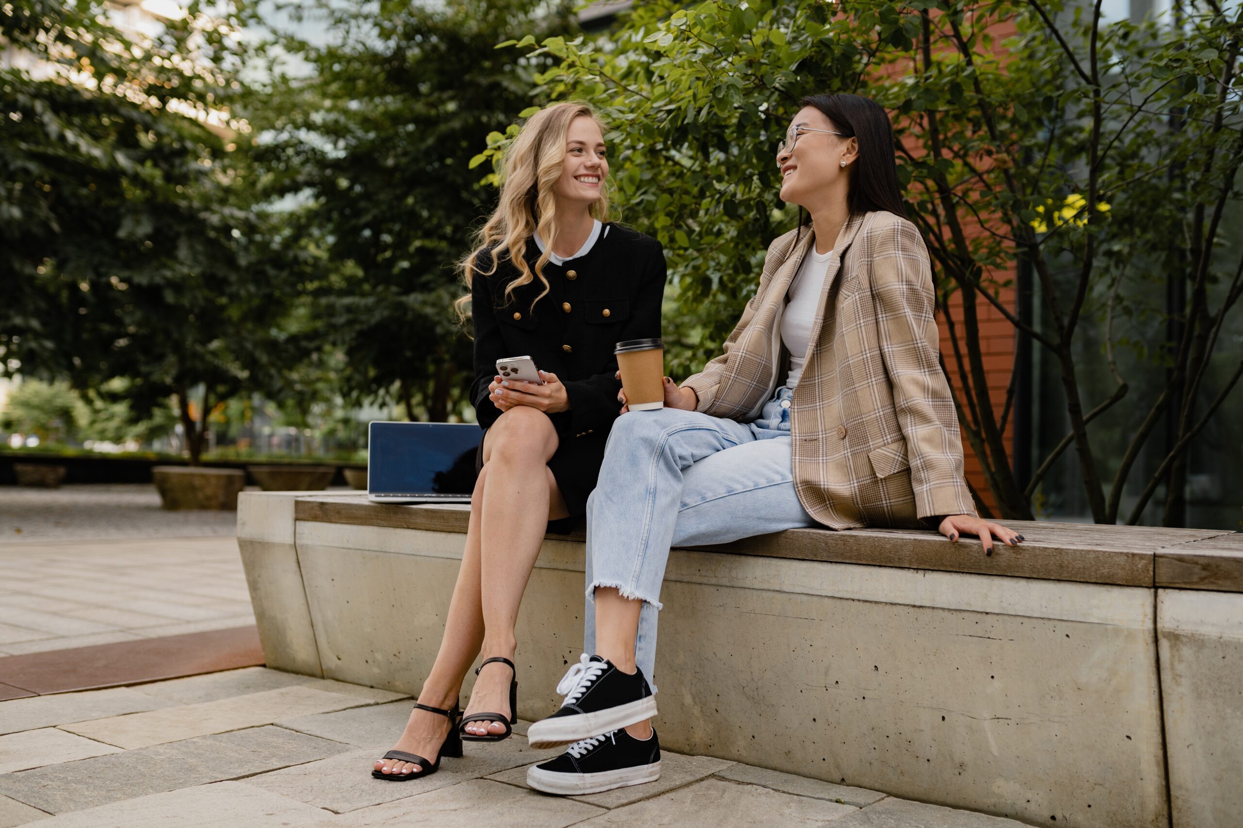 Two people sit outside on a bench.