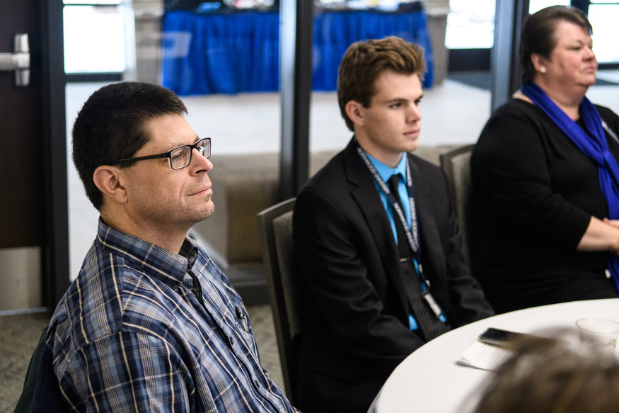 Three people sit at a round table, attentively listening during a meeting or conference, possibly discussing rankings for the Best Undergraduate Business Schools.