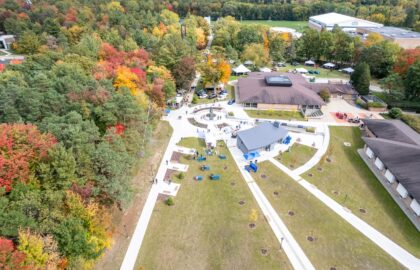 Aerial view of a campus courtyard at one of the universities in Michigan, with walkways, several buildings, scattered benches, and surrounding trees showing autumn foliage.